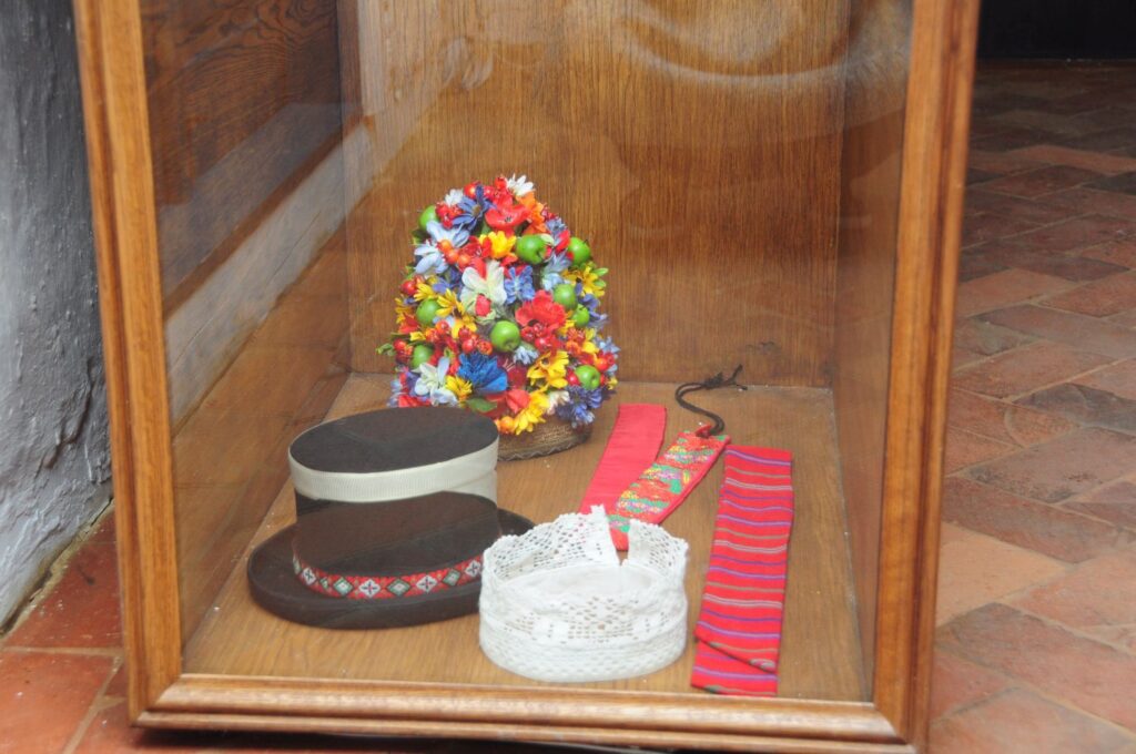 Gablotka muzealna z elementami tradycyjnego stroju ludowego, w tym kolorowym wiankiem, czepcem i pasem (kliknięcie powiększy zdjęcie).