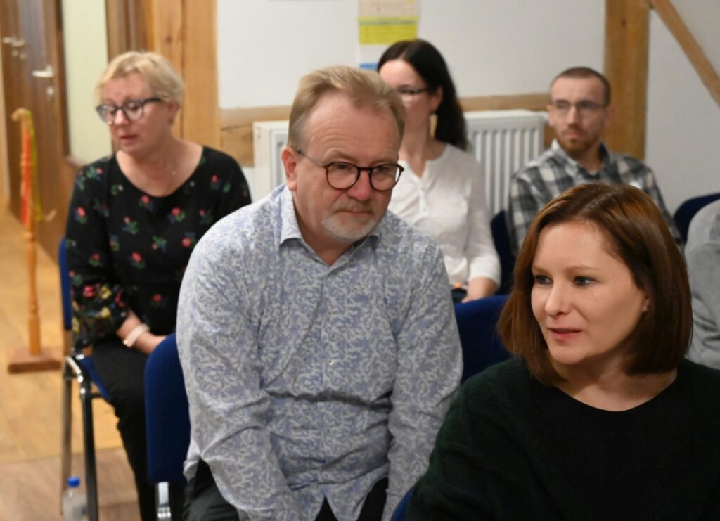 Uczestnicy seminarium siedzą w rzędach krzeseł w sali, prowadząc dyskusję (kliknięcie powiększy zdjęcie).