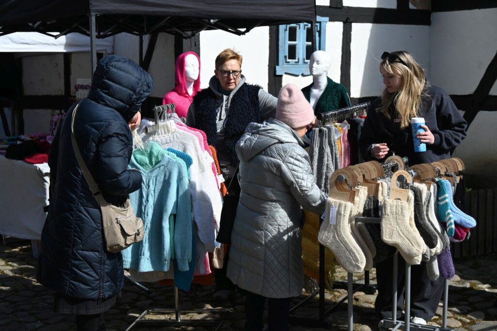 Odwiedzający oglądają i przeglądają ubrania oraz rękodzieło na stoisku podczas jarmarku (kliknięcie powiększy zdjęcie).