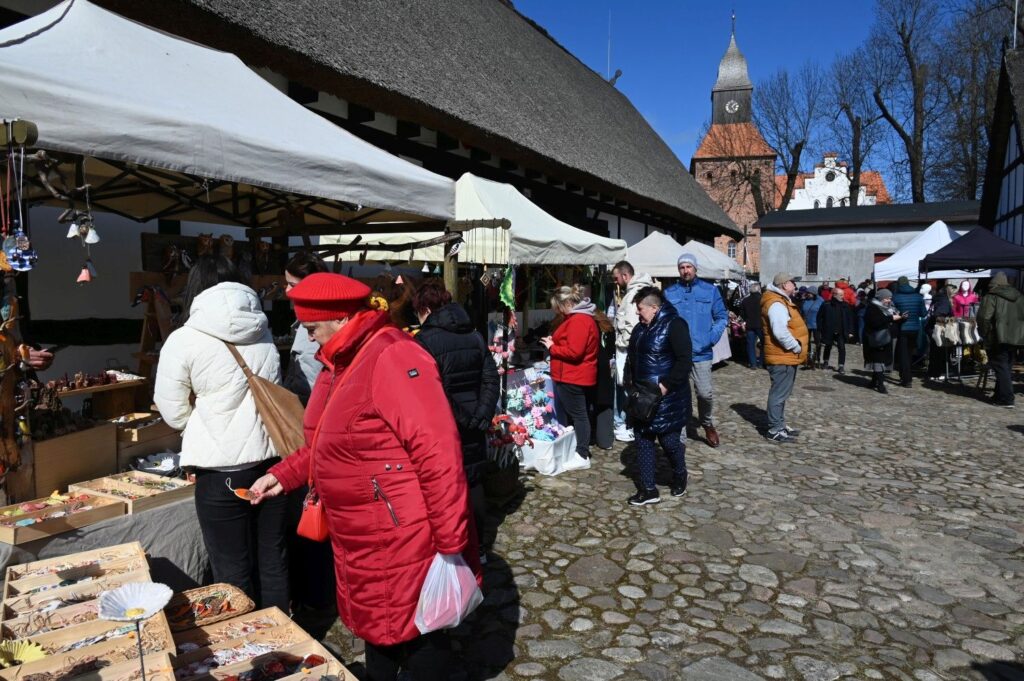 Odwiedzający jarmark oglądają rękodzieło i ozdoby wielkanocne na stoiskach ustawionych na dziedzińcu Zagrody (kliknięcie powiększy zdjęcie).