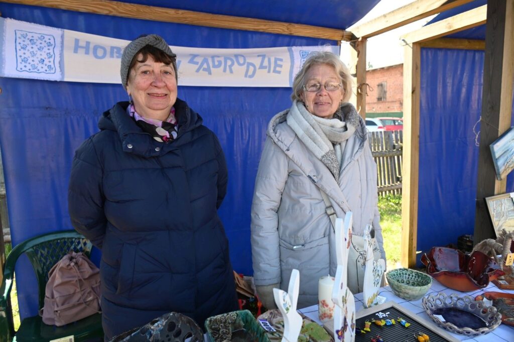 Dwie kobiety stoją przy stoisku z rękodziełem i ozdobami wielkanocnymi podczas jarmarku (kliknięcie powiększy zdjęcie).