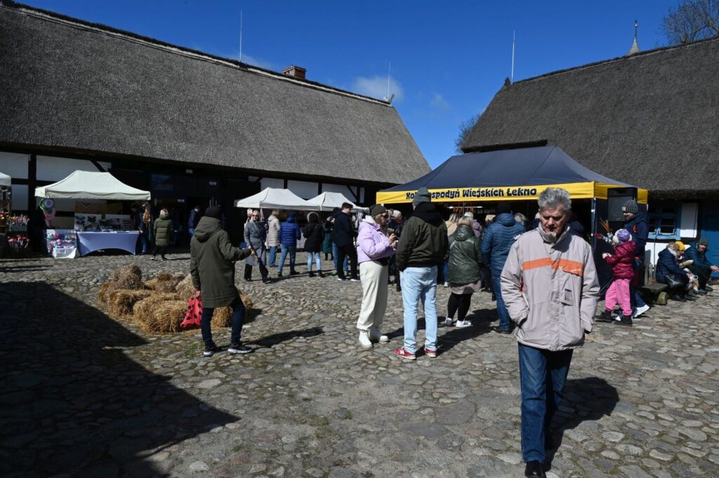 Odwiedzający spacerują między stoiskami jarmarku wielkanocnego na dziedzińcu Zagrody Jamneńskiej (kliknięcie powiększy zdjęcie).