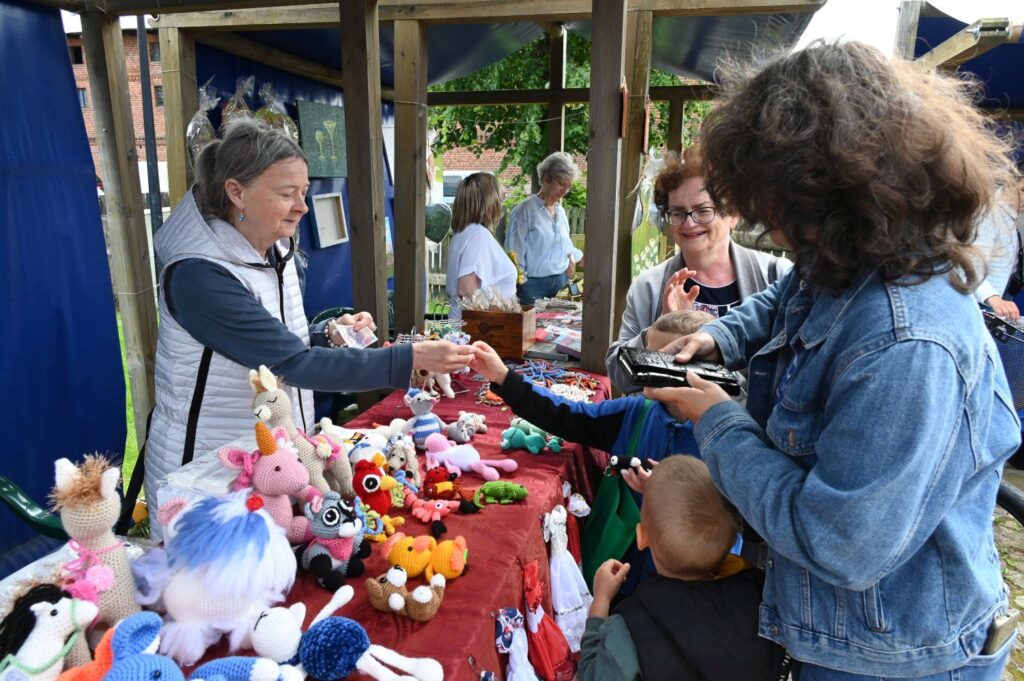 Kobieta dokonująca zakupu zabawek i maskotek na stoisku rękodzielniczym podczas jarmarku (kliknięcie powiększy zdjęcie).