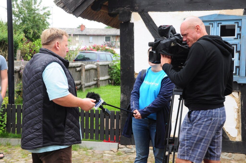 Ekipa telewizyjna nagrywająca materiał podczas rozmowy z uczestnikami wydarzenia na terenie jarmarku (kliknięcie powiększy zdjęcie).