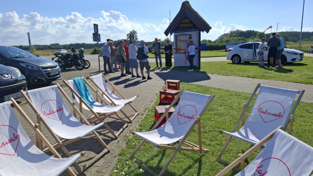 Leżaki ustawione na placu podczas wydarzenia plenerowego, w tle uczestnicy i samochody (kliknięcie powiększy zdjęcie)