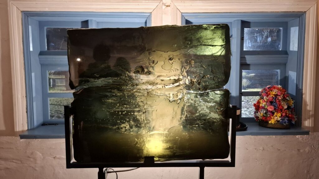 Instalacja artystyczna z podświetlonym szklanym panelem ustawionym na stojaku przed oknem (kliknięcie powiększy zdjęcie)