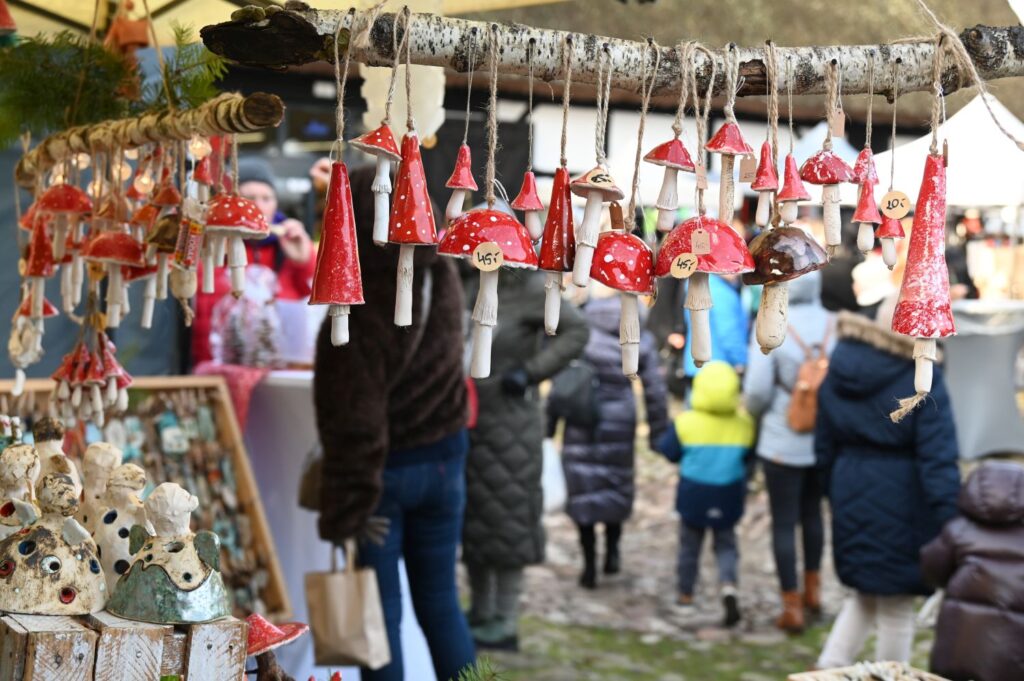 Wiszące ozdoby w kształcie czerwonych muchomorów i figurek ceramicznych na stoisku rękodzielniczym (kliknięcie powiększy zdjęcie).