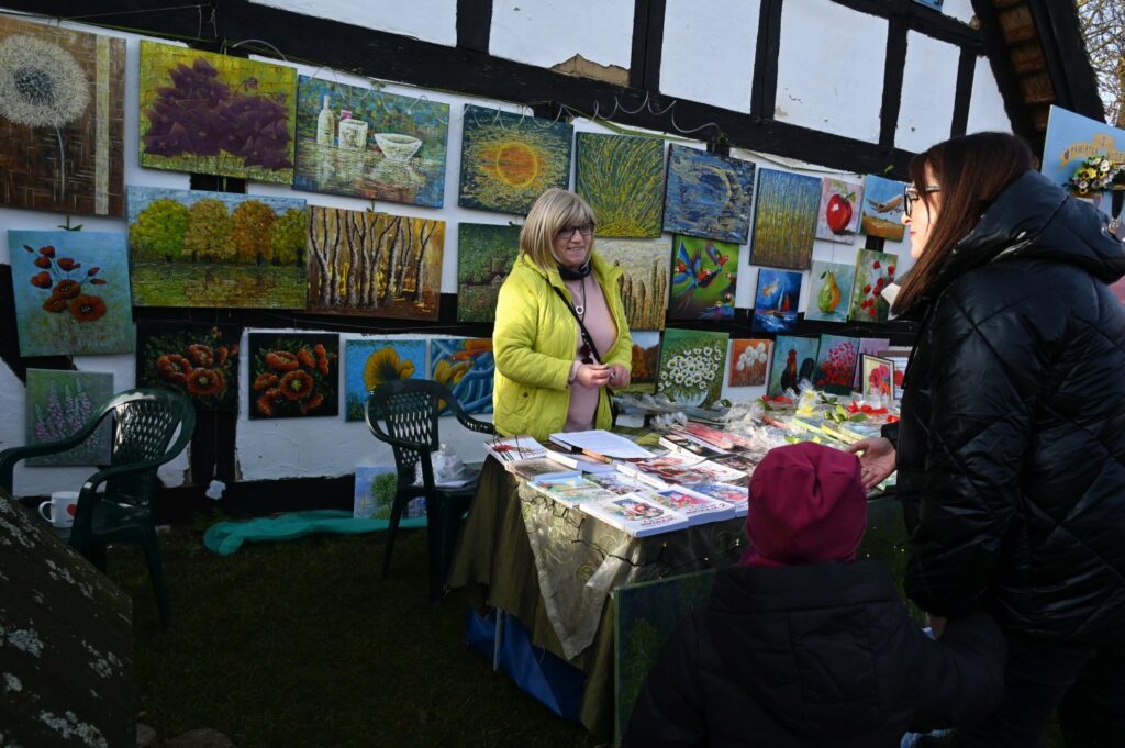 Stoisko z obrazami i rękodziełem artystycznym obsługiwane przez wystawców na jarmarku jamneńskim (kliknięcie powiększy zdjęcie).