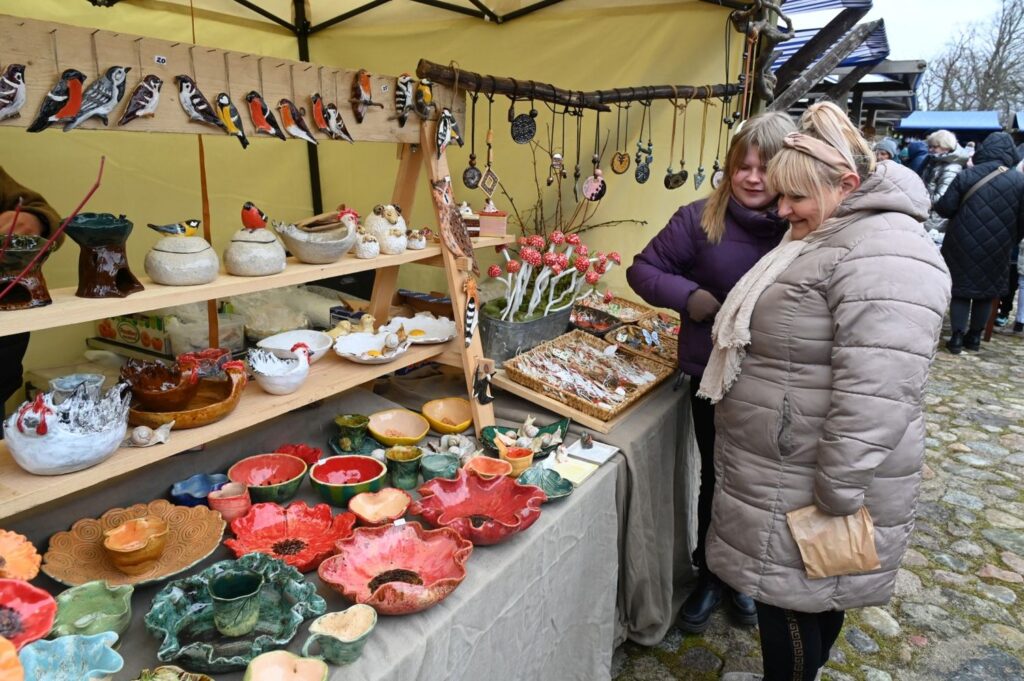 Odwiedzające oglądają ceramiczne naczynia i ozdoby wystawione na stoisku z rękodziełem (kliknięcie powiększy zdjęcie).