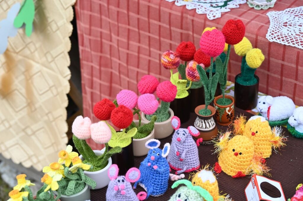 Szydełkowe figurki zwierząt i kolorowe kwiaty ustawione na stole z wielkanocnymi ozdobami (kliknięcie powiększy zdjęcie)