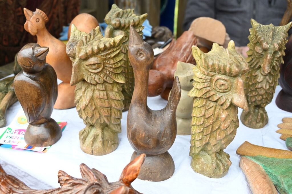 Drewniane rzeźby ptaków, w tym sowy i inne figurki zwierząt ustawione na stole wystawowym (kliknięcie powiększy zdjęcie).