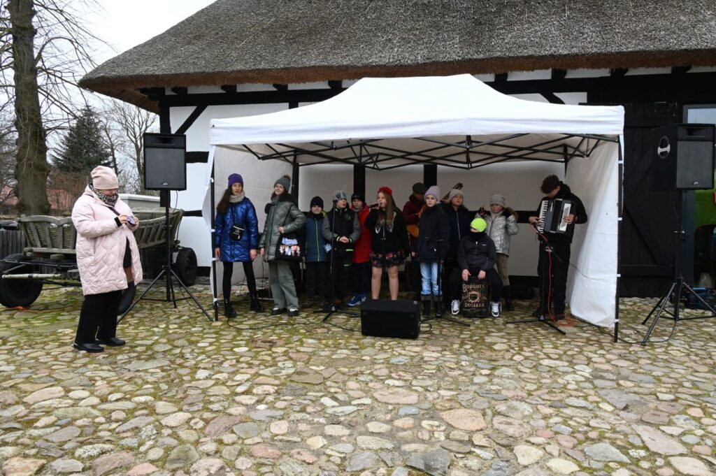 Występ dziecięcego zespołu wokalnego odbywa się na małej scenie ustawionej przed budynkiem skansenu (kliknięcie powiększy zdjęcie).