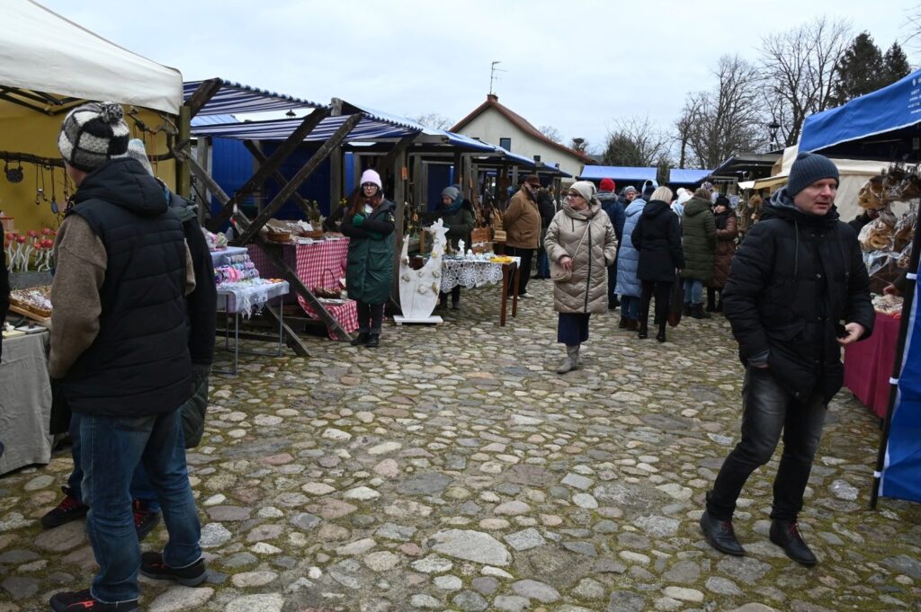 Odwiedzający spacerują między rzędami stoisk ustawionych na brukowanym dziedzińcu Zagrody (kliknięcie powiększy zdjęcie).