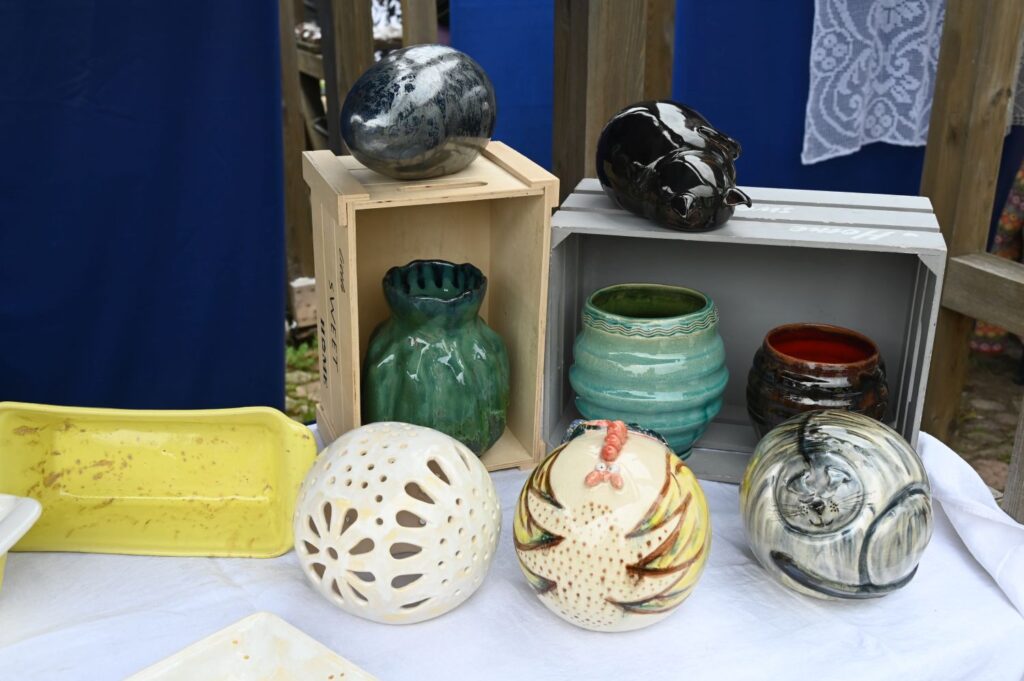 Ceramiczne naczynia i dekoracje ustawione na stole wystawowym, wśród nich wazony, misy i ozdobne kule (kliknięcie powiększy zdjęcie).