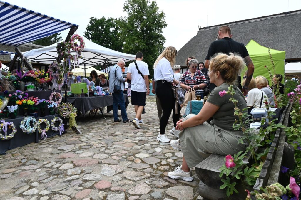 Odwiedzający spacerują między stoiskami z wiankami i dekoracjami kwiatowymi ustawionymi na brukowanym placu (kliknięcie powiększy zdjęcie).