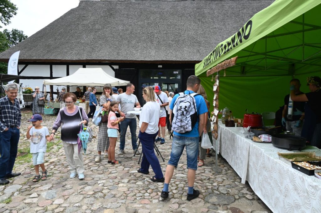 Rodziny z dziećmi przechodzą obok stoiska gastronomicznego ustawionego pod zielonym namiotem (kliknięcie powiększy zdjęcie).