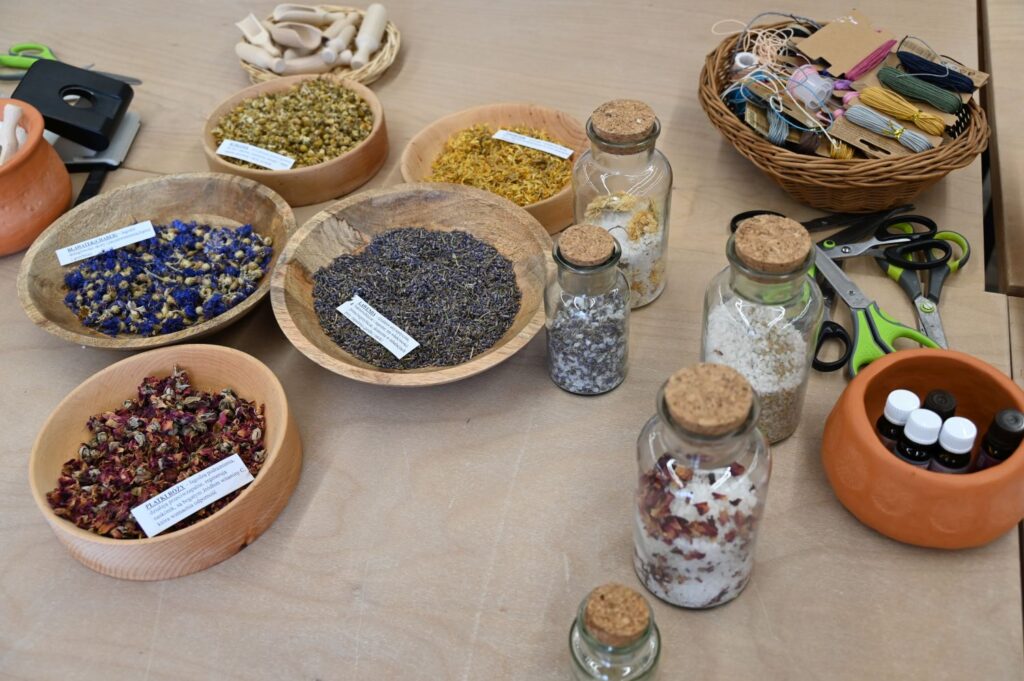 Stół z miseczkami suszonych ziół, kwiatów i przypraw oraz słoiczkami przygotowanymi do warsztatów (kliknięcie powiększy zdjęcie