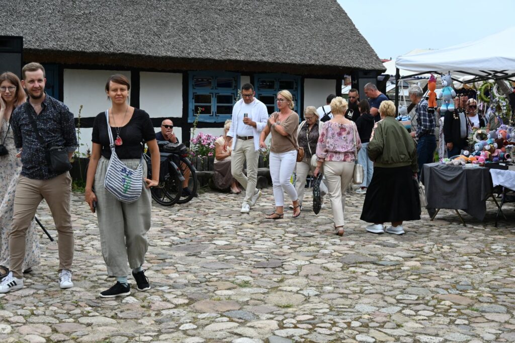 Tłum odwiedzających spaceruje między stoiskami jarmarku na dziedzińcu otoczonym budynkami o konstrukcji szachulcowej (kliknięcie powiększy zdjęcie).