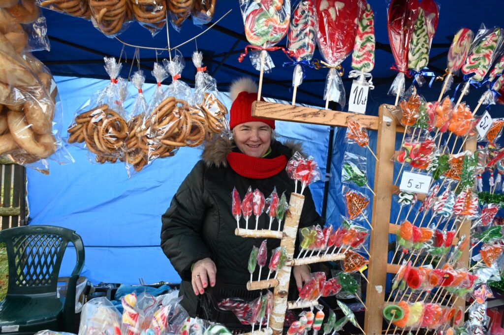 Stoisko ze słodyczami, na którym sprzedawane są kolorowe lizaki i precle, a sprzedawczyni siedzi za ladą (kliknięcie powiększy zdjęcie).