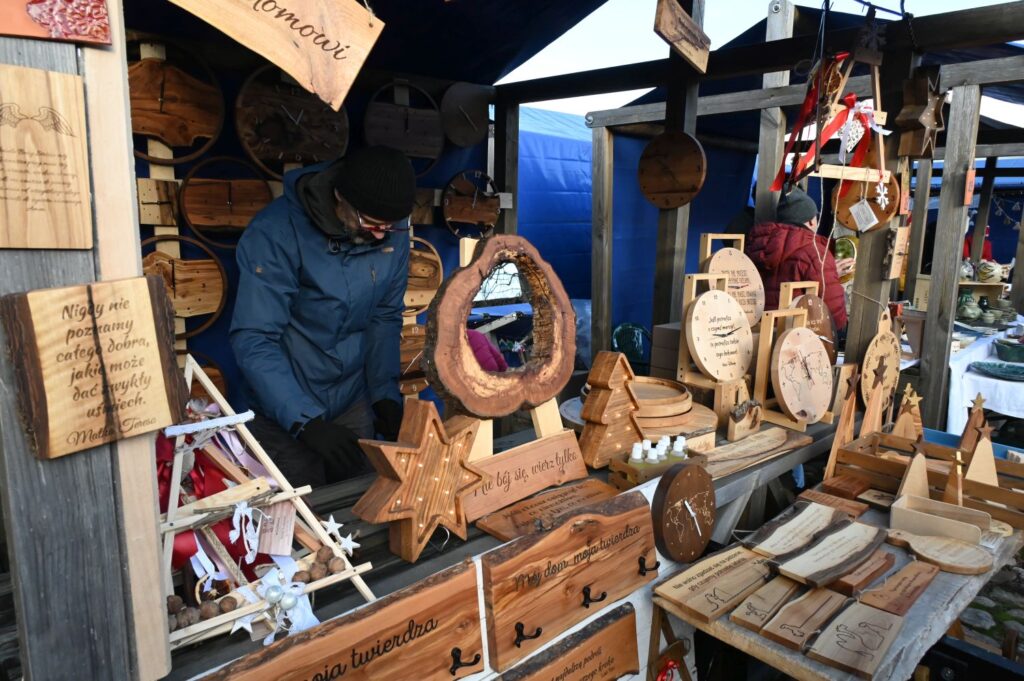 Drewniane wyroby rękodzielnicze, w tym ozdoby i deski, prezentowane na stoisku (kliknięcie powiększy zdjęcie).
