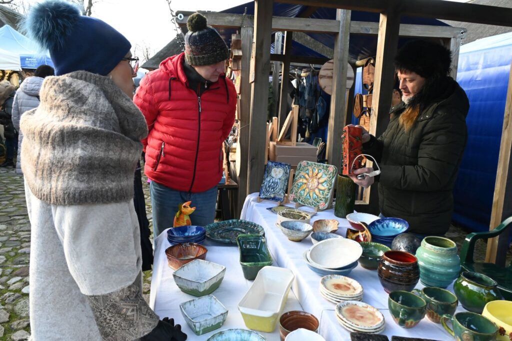 Stoisko z ręcznie wykonaną ceramiką, przy którym dwie osoby oglądają miski i naczynia (kliknięcie powiększy zdjęcie).