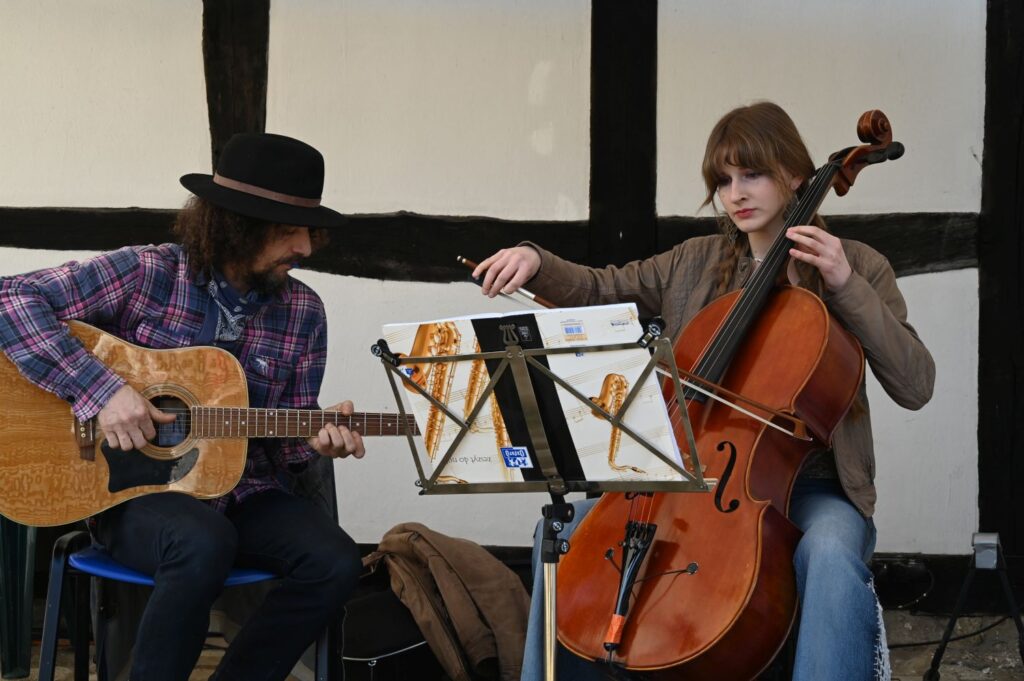 Duet muzyczny wykonuje utwór na gitarze i wiolonczeli, korzystając z nut ustawionych na pulpicie (kliknięcie powiększy zdjęcie).