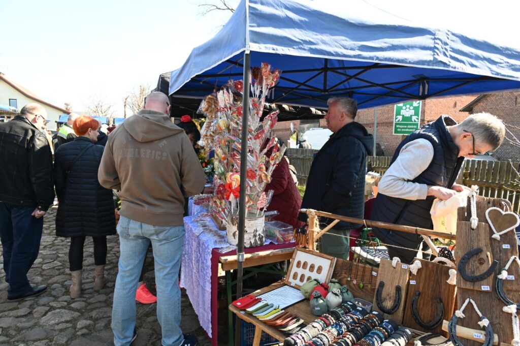 Stoisko z rękodziełem i ozdobami, przy którym odwiedzający przeglądają oferowane produkty (kliknięcie powiększy zdjęcie).