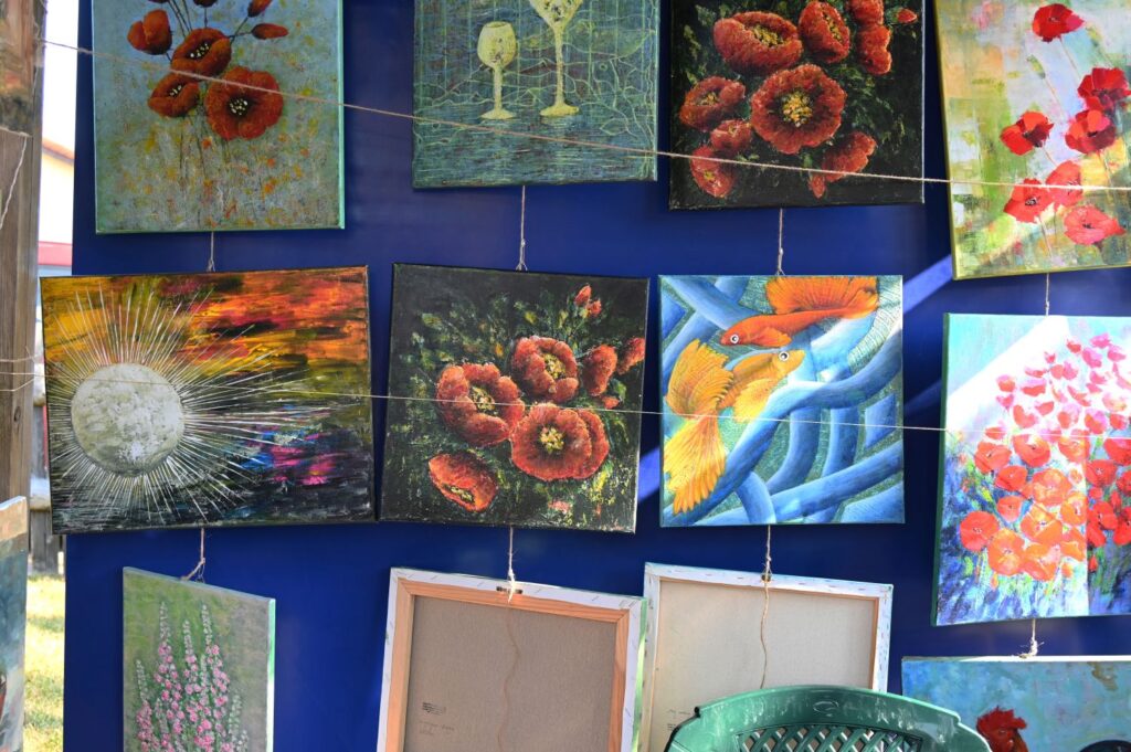 Kolorowe obrazy z motywami kwiatów i abstrakcji prezentowane na stoisku podczas jarmarku (kliknięcie powiększy zdjęcie).