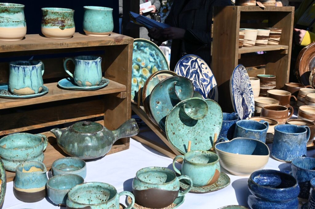 Stoisko z ręcznie wykonaną ceramiką, gdzie wystawione są kubki, talerze i naczynia (kliknięcie powiększy zdjęcie).