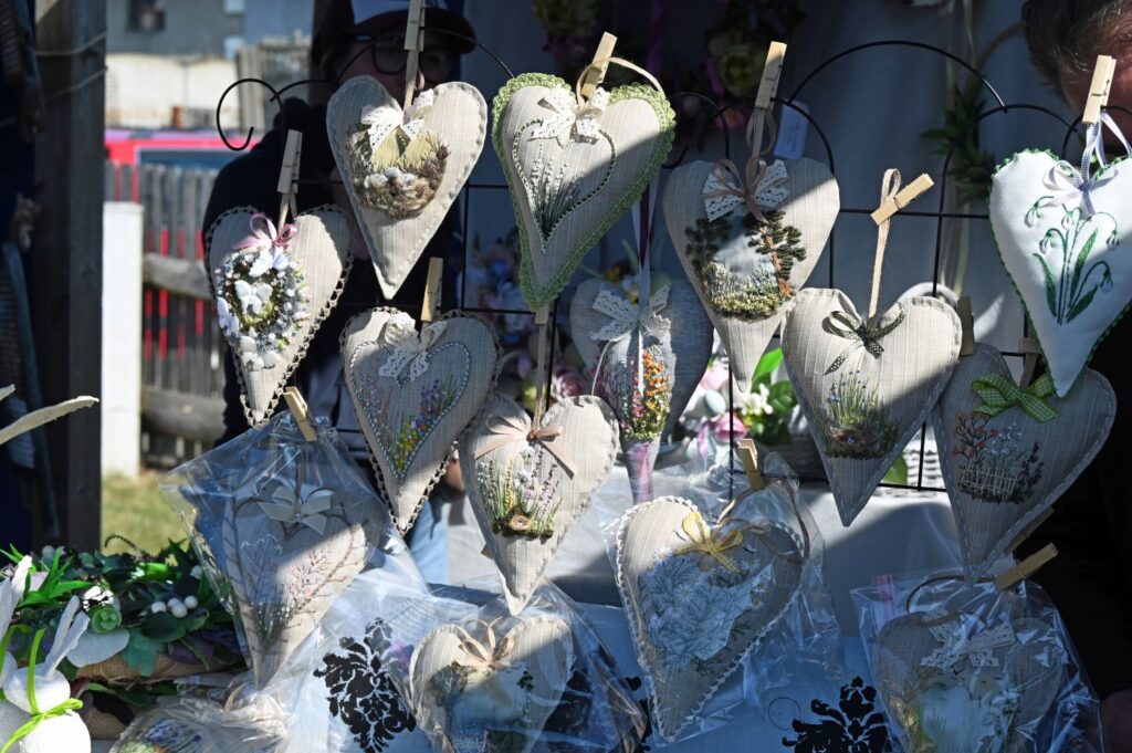 Dekoracyjne serca z tkaniny i koronki zawieszone jako ozdoby rękodzielnicze na stoisku (kliknięcie powiększy zdjęcie).