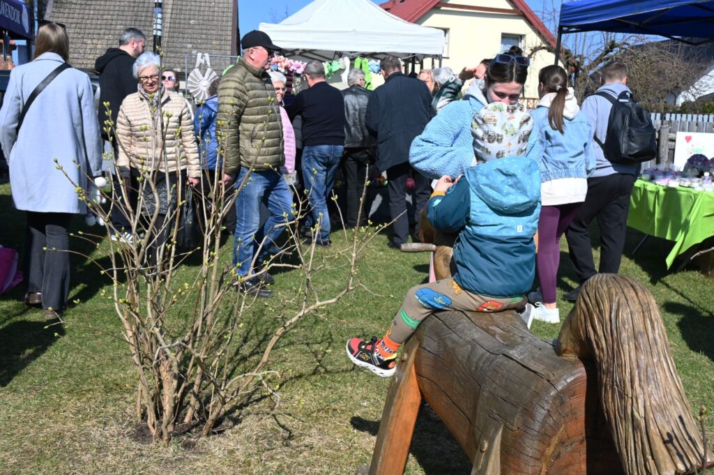 Odwiedzający gromadzą się przy stoisku na trawie podczas wielkanocnego jarmarku (kliknięcie powiększy zdjęcie).