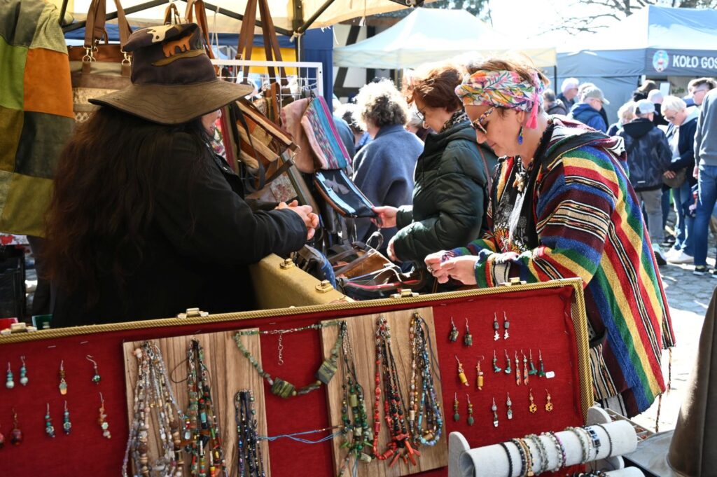 Stoisko z biżuterią, gdzie odwiedzające oglądają naszyjniki i bransoletki podczas jarmarku (kliknięcie powiększy zdjęcie).