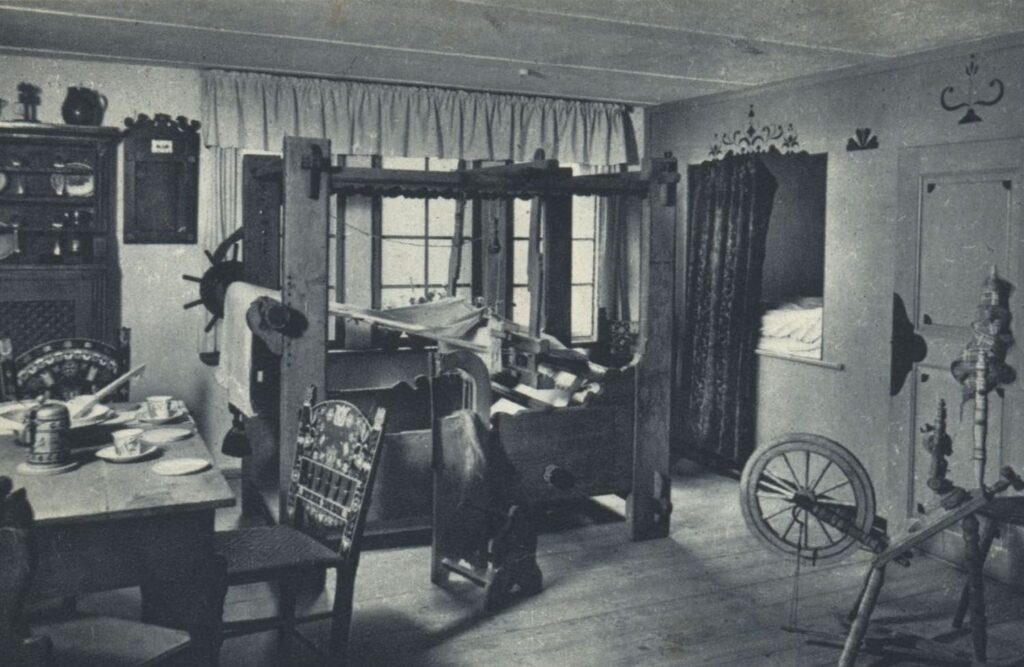 Wnętrze „izby jamneńskiej” z lat 30. XX wieku z krosnem tkackim, stołem, krzesłami oraz tradycyjnym wyposażeniem domowym prezentowanym na ekspozycji muzealnej (kliknięcie powiększy zdjęcie).