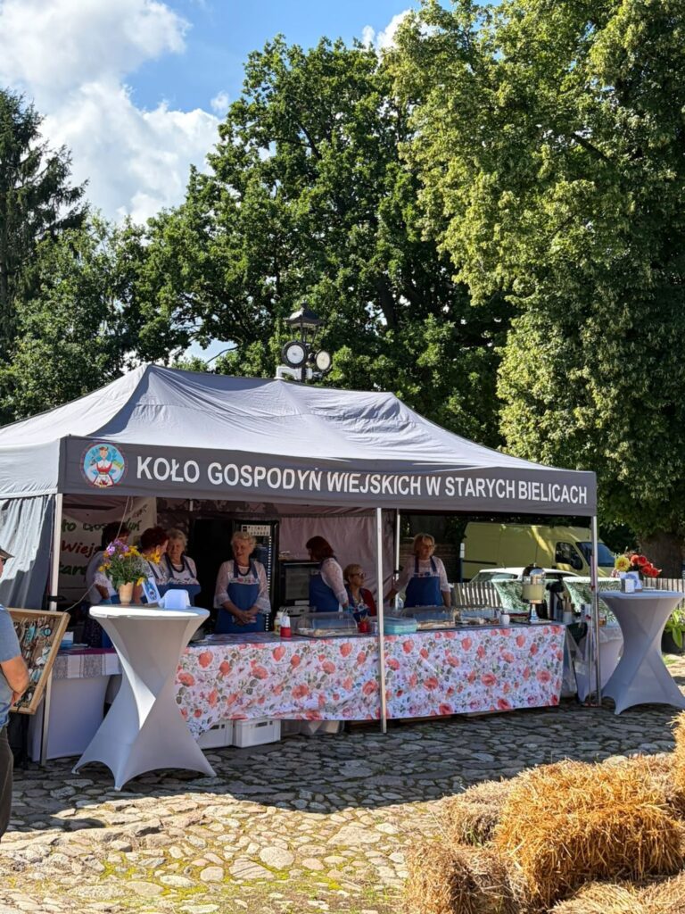 Stoisko Koła Gospodyń Wiejskich w Starych Bielicach; przed namiotem ustawiono stoły z produktami i potrawami przygotowanymi przez członkinie koła (kliknięcie powiększy zdjęcie).