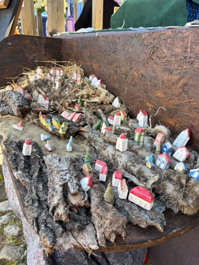 Stoisko z rękodziełem przedstawiającym miniaturowe domki i inne ozdoby umieszczone na kawałkach kory i drewnie. (kliknięcie powiększy zdjęcie).